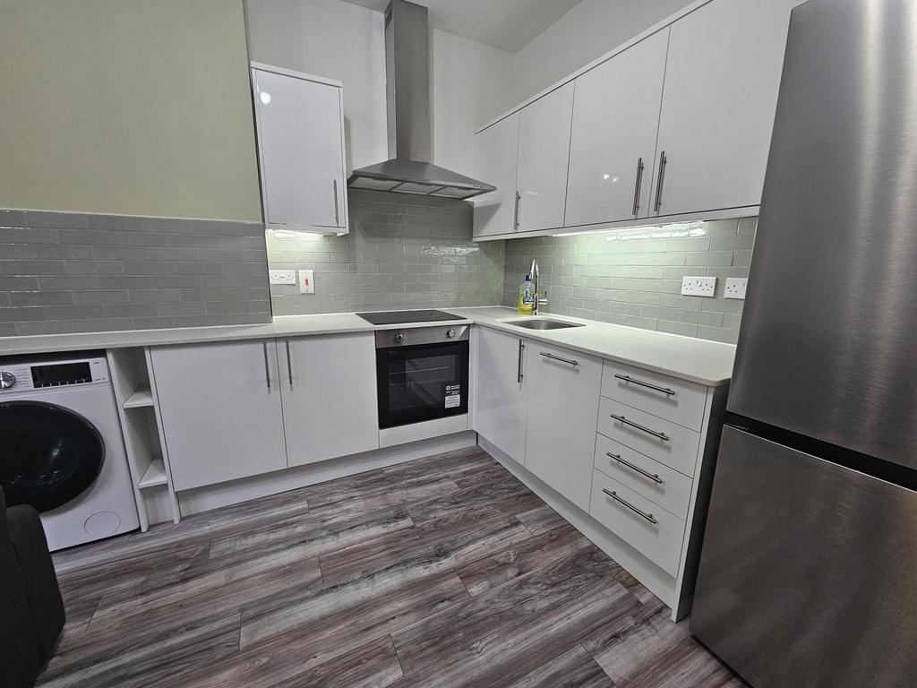 Modern fitted kitchen with white cabinetry, int...