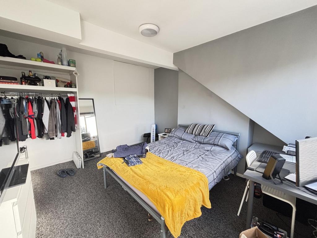 A well-lit bedroom featuring a double bed, a de...