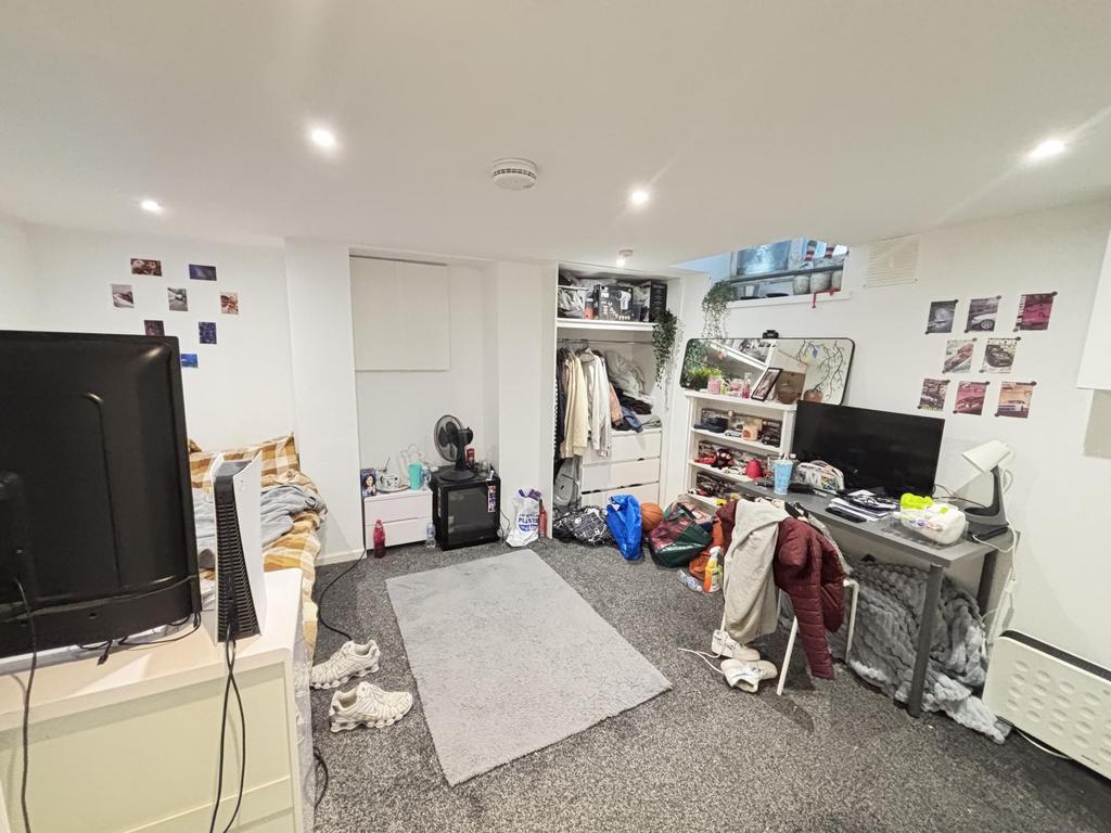 A modest living room with a TV, some scattered ...