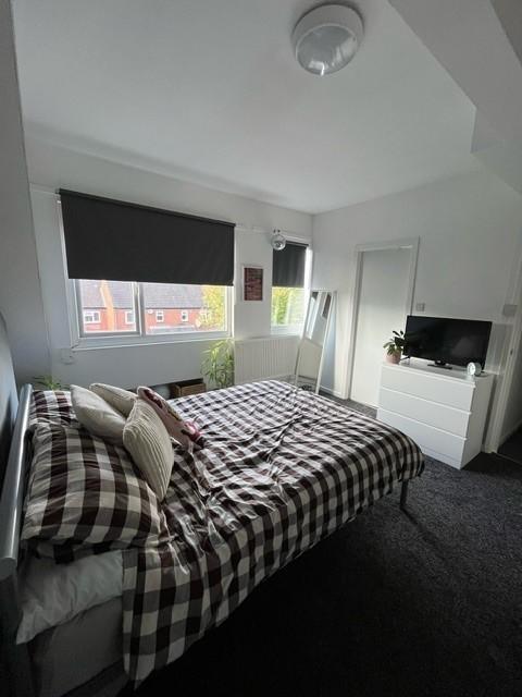 A cozy bedroom featuring a double bed with chec...