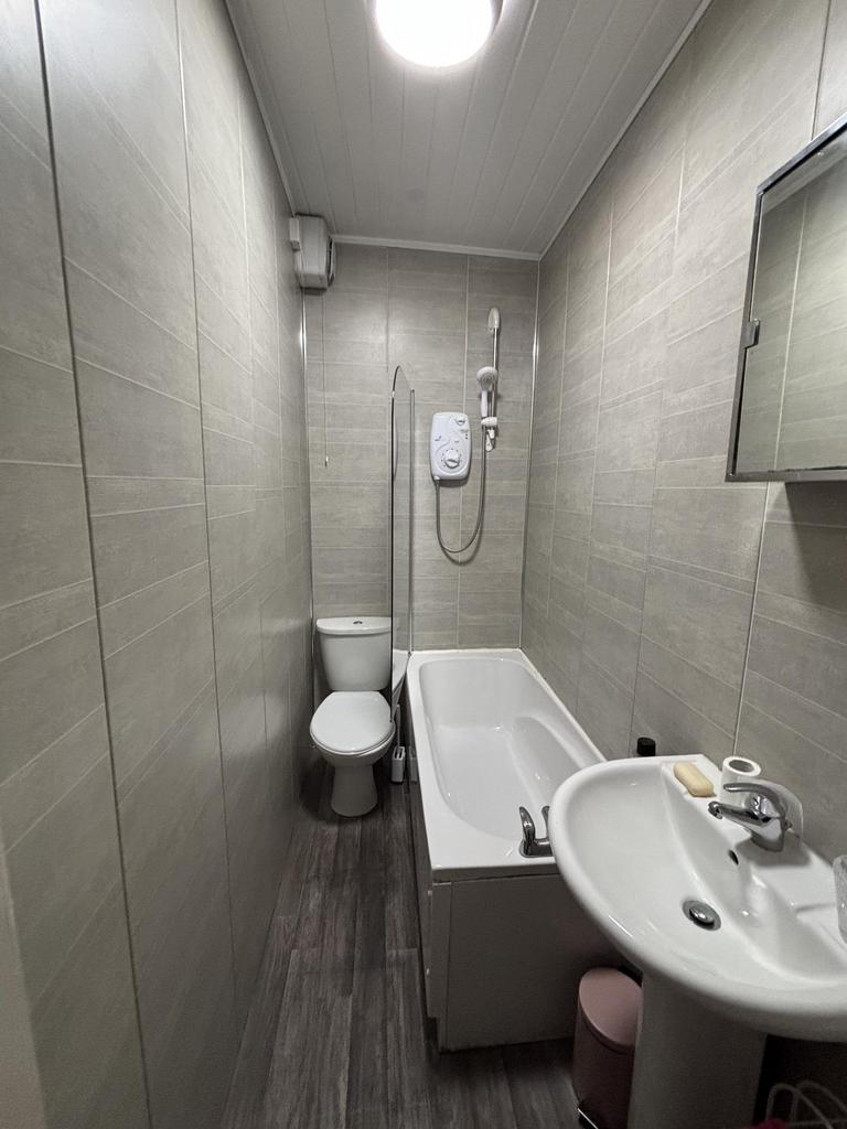 A clean, modern bathroom featuring a shower, to...