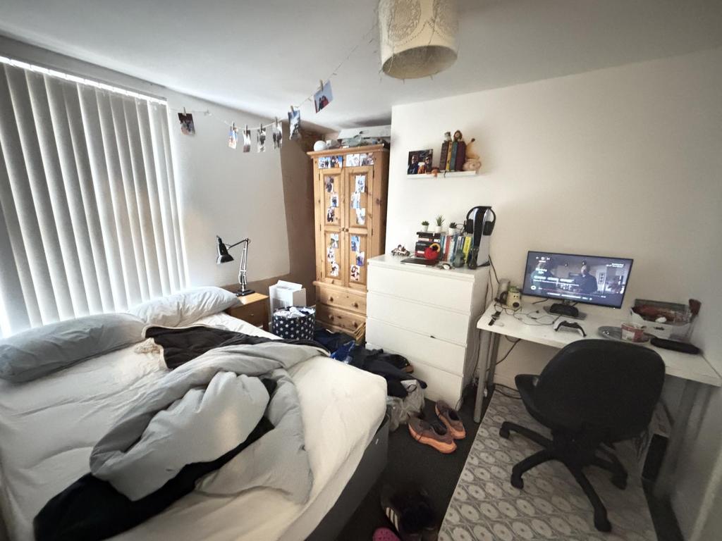 A cozy bedroom featuring a single bed, a desk w...