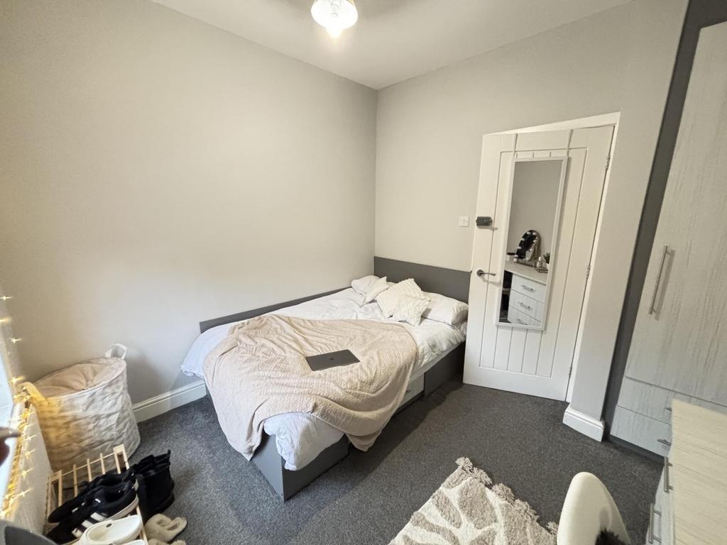 A well-lit, neat bedroom featuring a comfortabl...