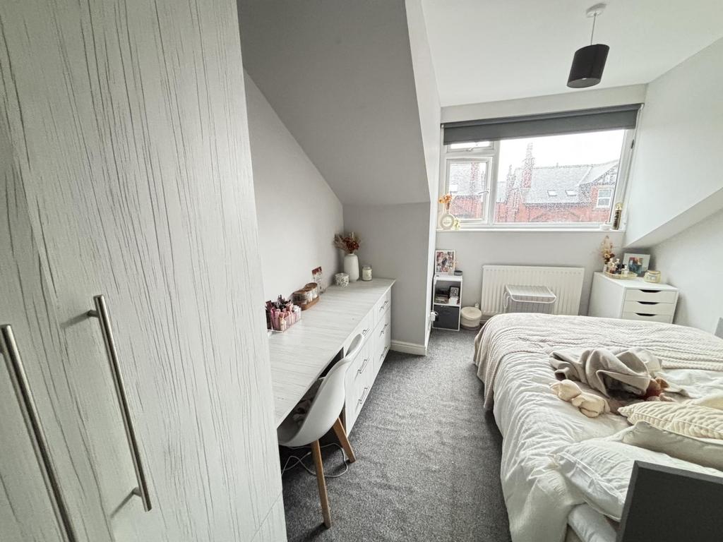 A well-lit, tidy bedroom featuring a comfortabl...