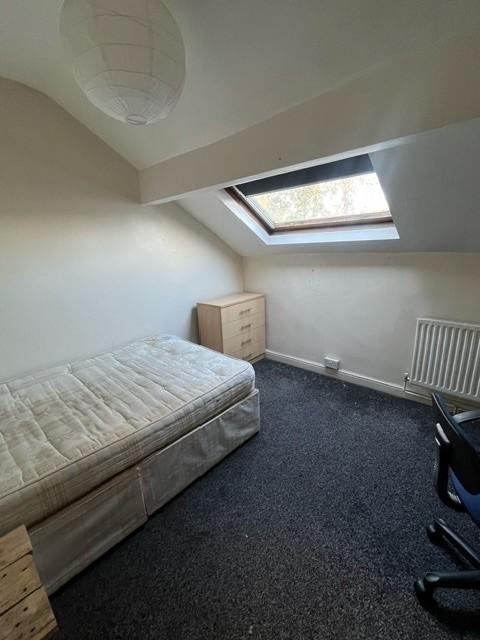 A cozy single bedroom featuring a mattress, und...