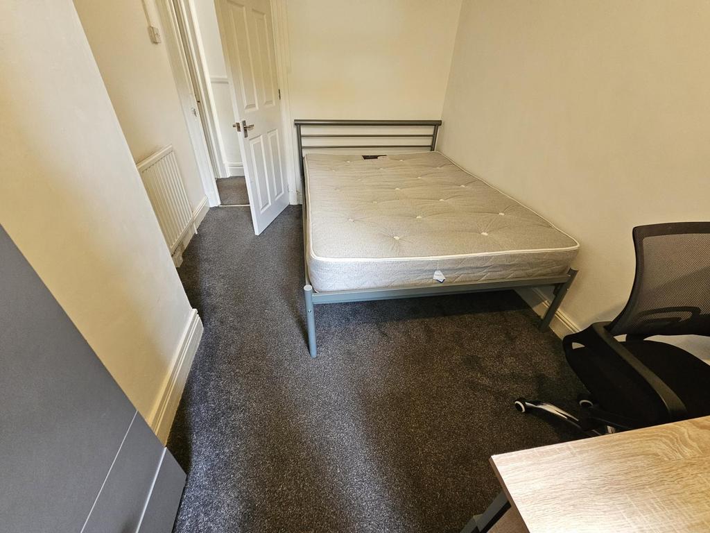 A modest-sized bedroom featuring a double bed f...