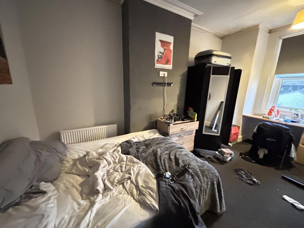 A cozy bedroom featuring a bed with rumpled bed...