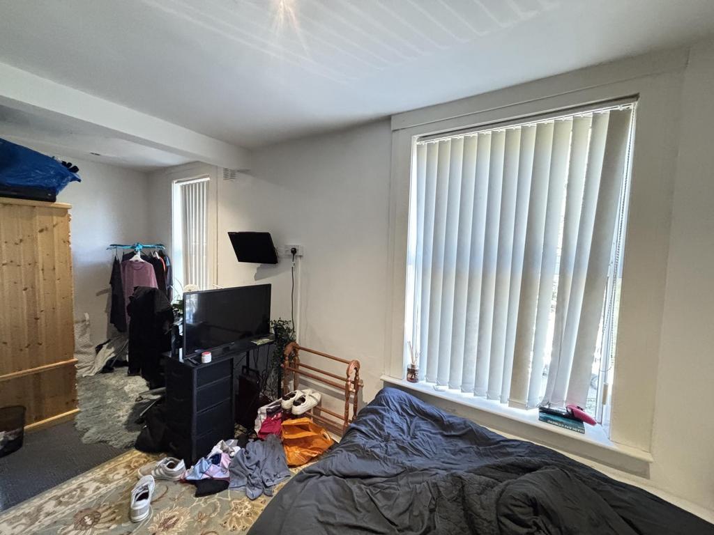A modest bedroom featuring a single bed, a wind...