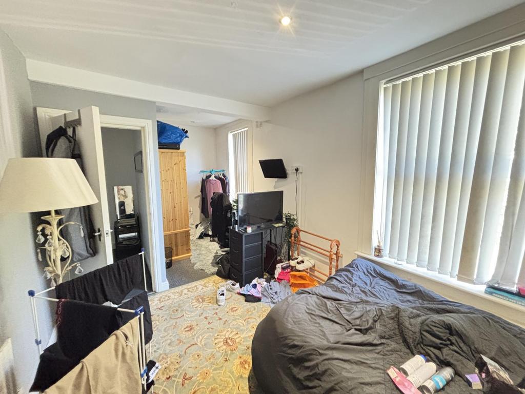 A cozy bedroom featuring a double bed near larg...