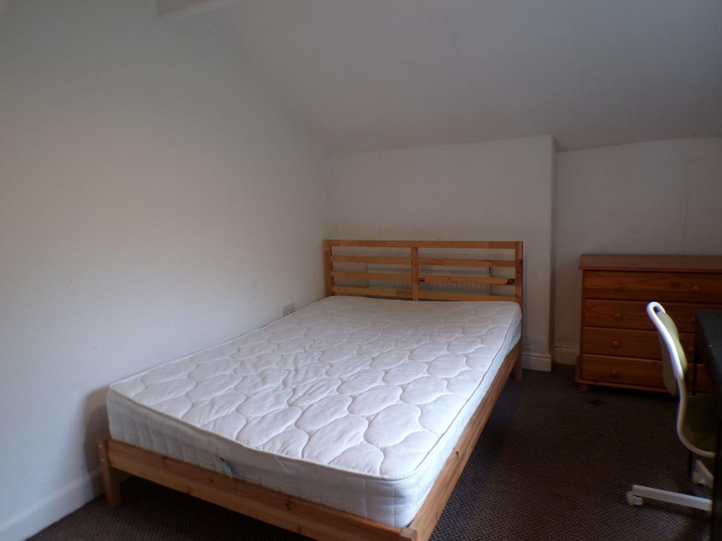 Bright, simply furnished bedroom with a wooden ...