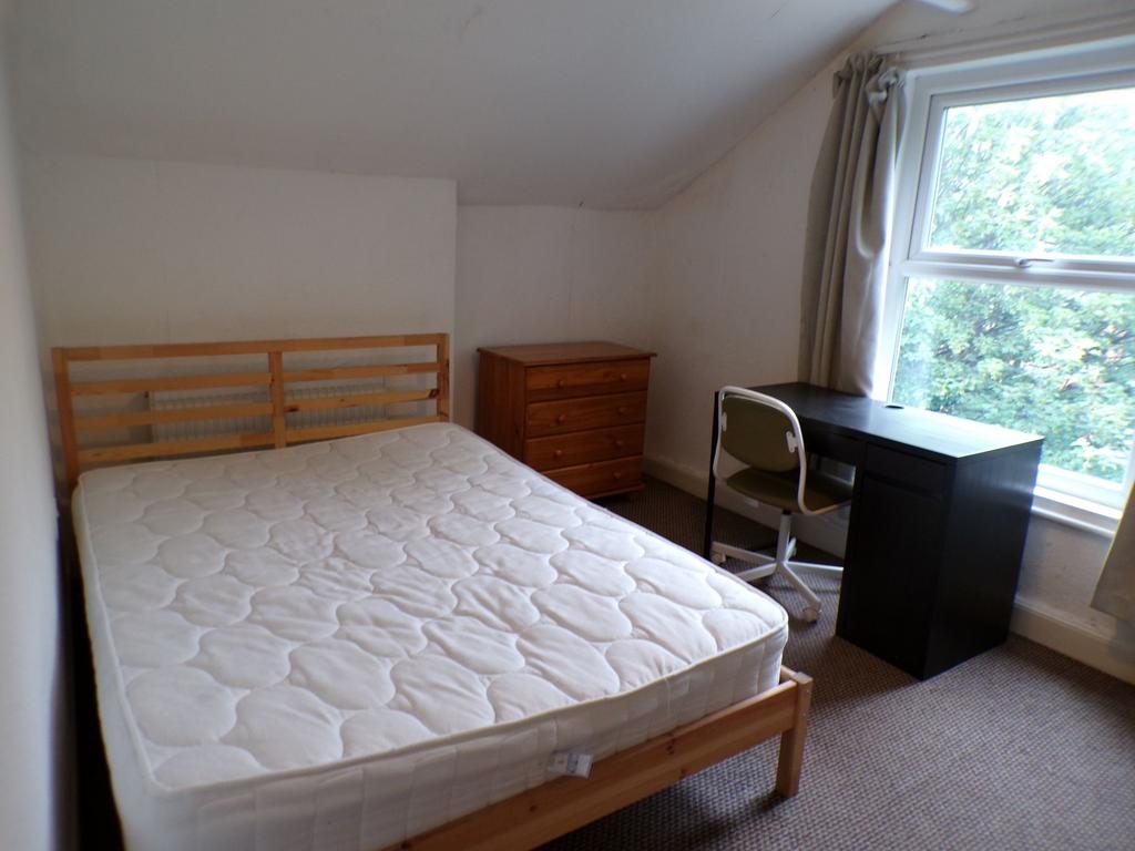 Bright, simply furnished bedroom with a double ...