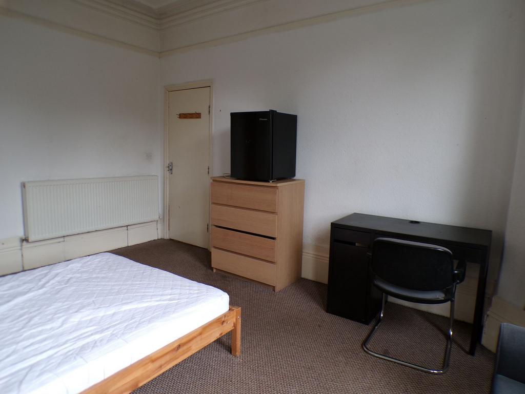 Bright simple bedroom with a wooden bed frame a...