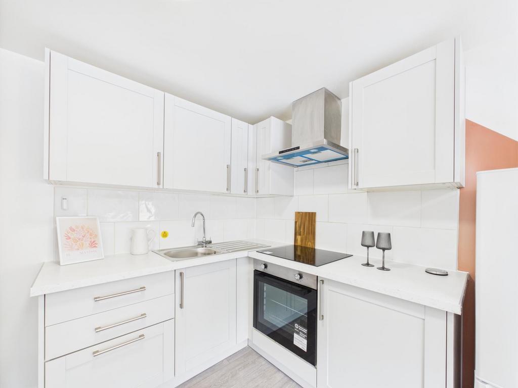 Bright modern white kitchen with L-shaped cabin...