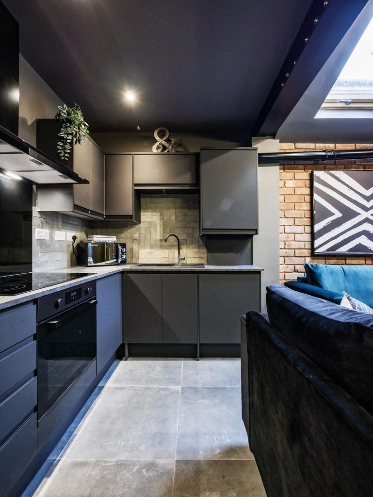 Modern, sleek kitchen with dark cabinetry, ampl...