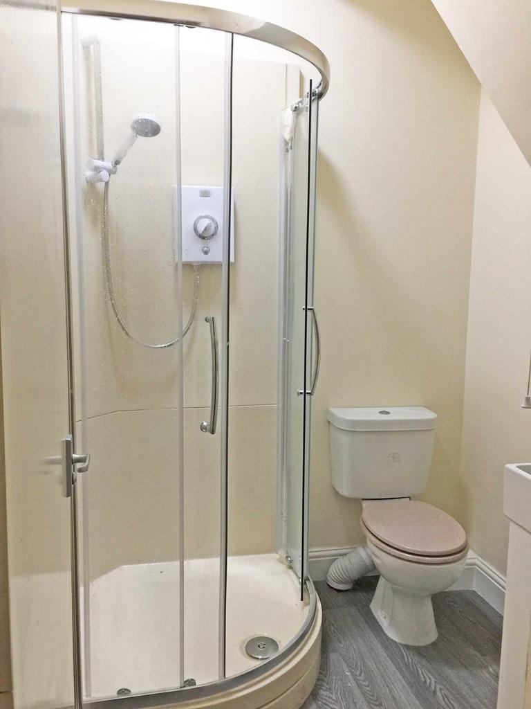 Bright, tidy bathroom featuring a curved-glass ...