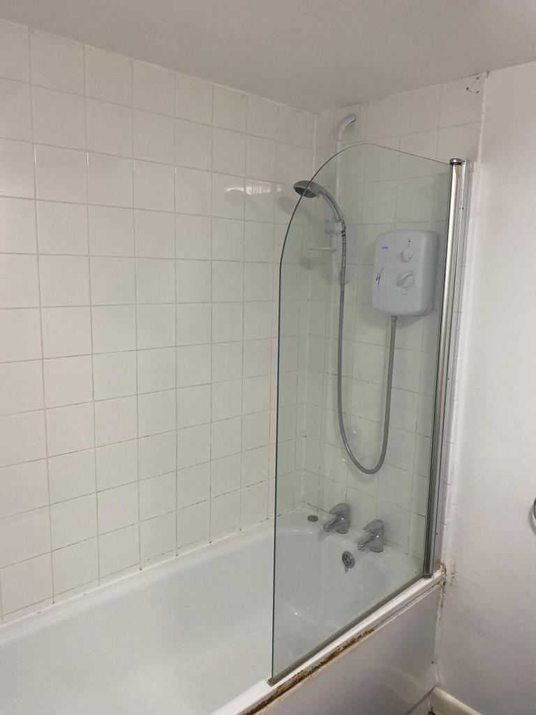 A functional bathroom with a shower featuring a...