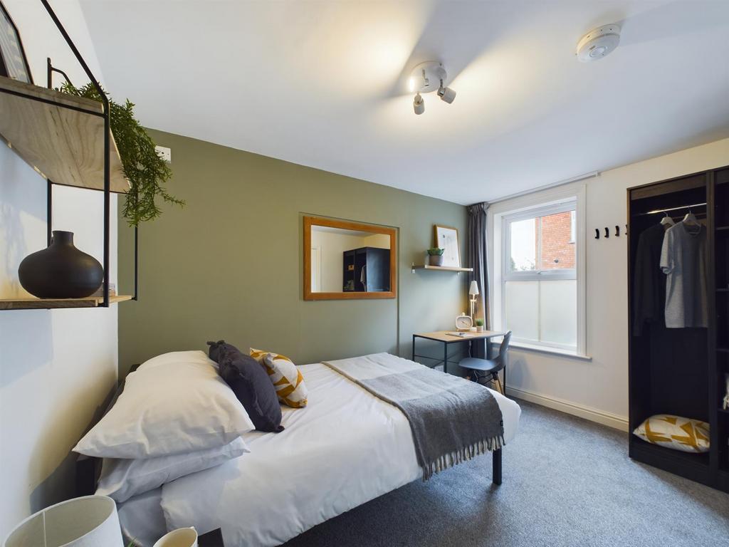 A bright and welcoming bedroom featuring a comf...