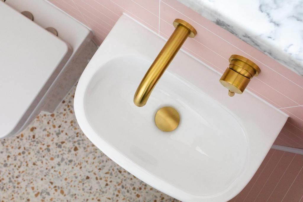 Stylish bathroom washbasin with modern gold-ton...