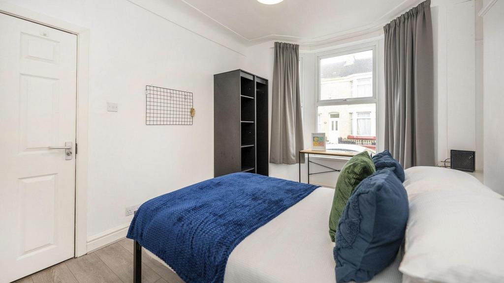 A bright and clean double bedroom featuring mod...