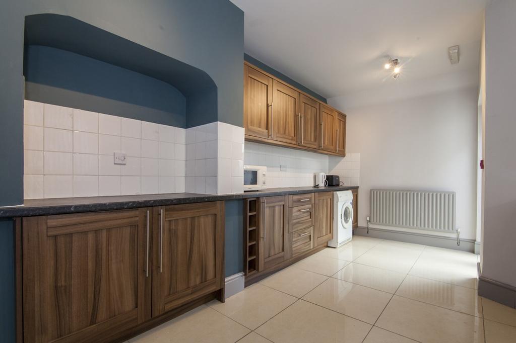A spacious and tidy kitchenette with modern cab...