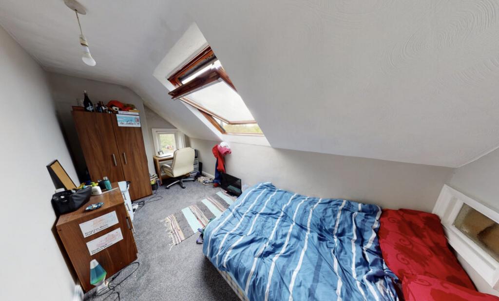 A cozy bedroom with a sloped ceiling, featuring...