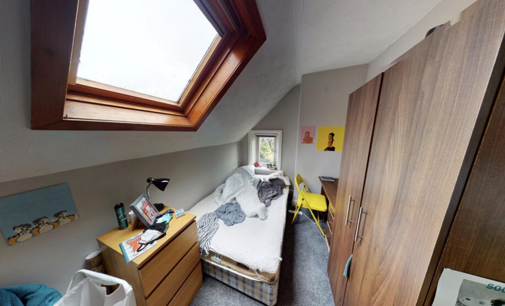 A well-lit bedroom with a large window bringing...
