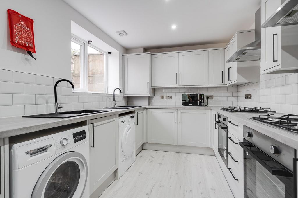 A bright, modern kitchen featuring white cabine...