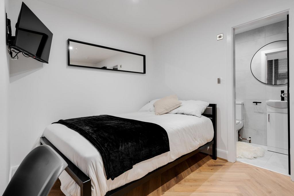 A tidy and well-lit student bedroom featuring a...