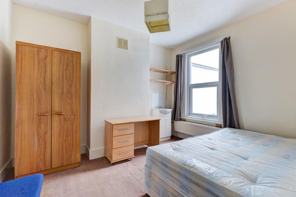 A bright and tidy bedroom featuring a large win...