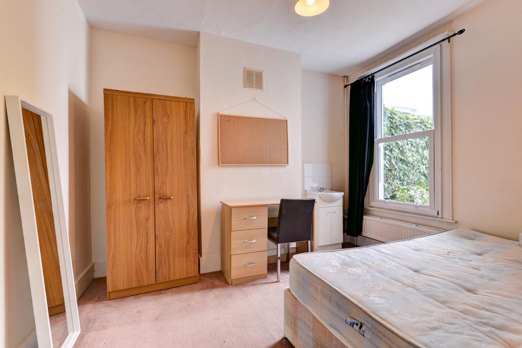 A clean, well-lit bedroom featuring a bed, ward...