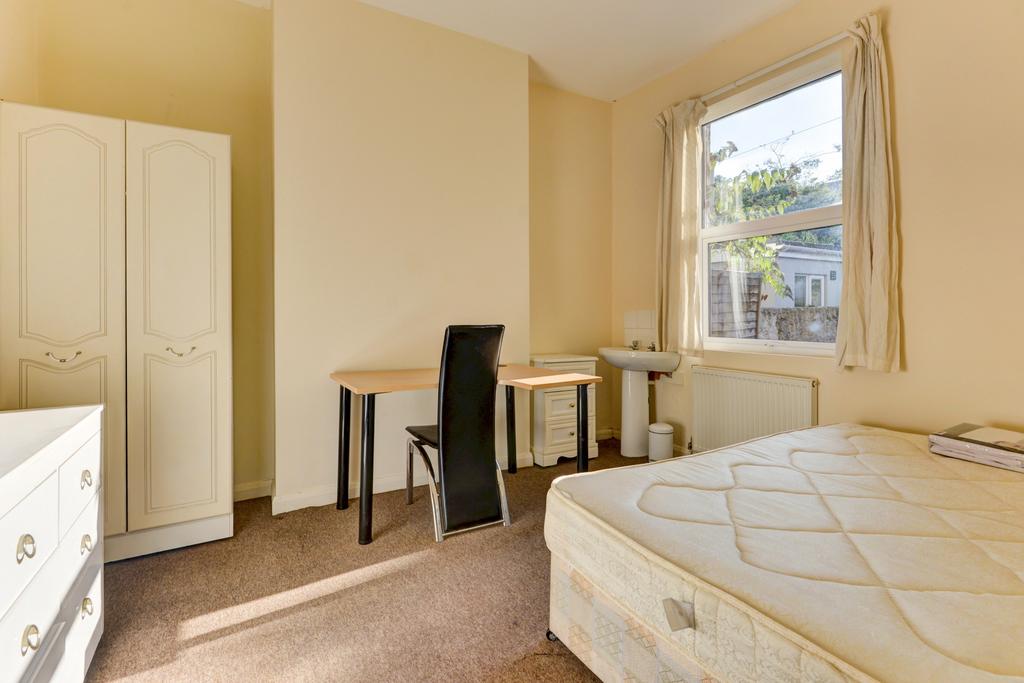 A well-lit, tidy bedroom featuring a comfortabl...