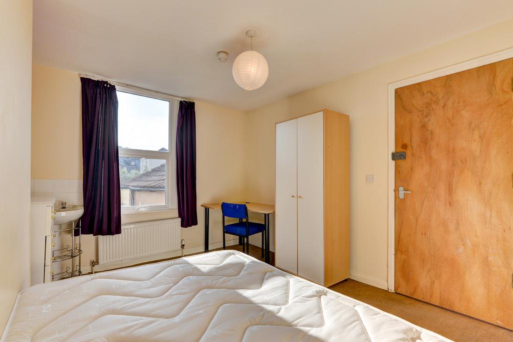 A cozy single bedroom featuring a neatly made b...