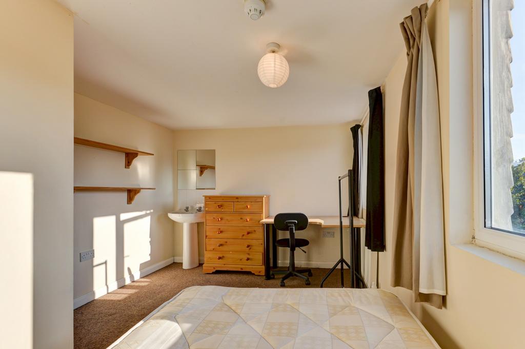 A bright and tidy bedroom with a large window a...