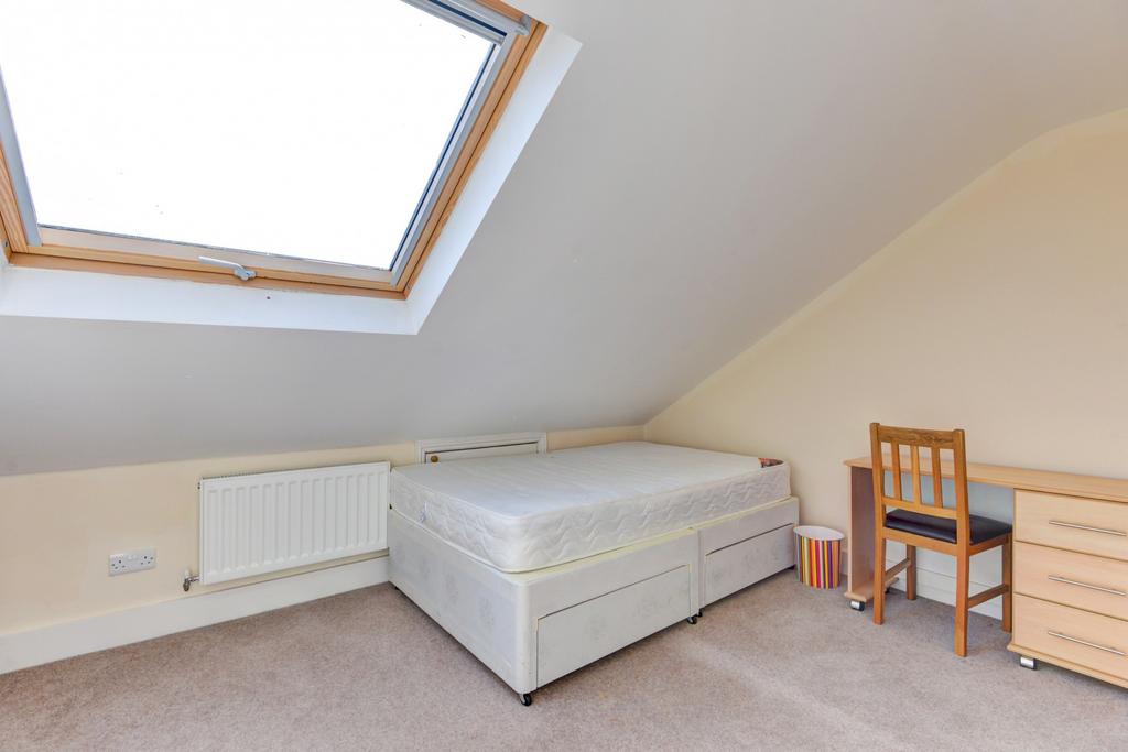 A cozy single bedroom featuring a bed, a study ...