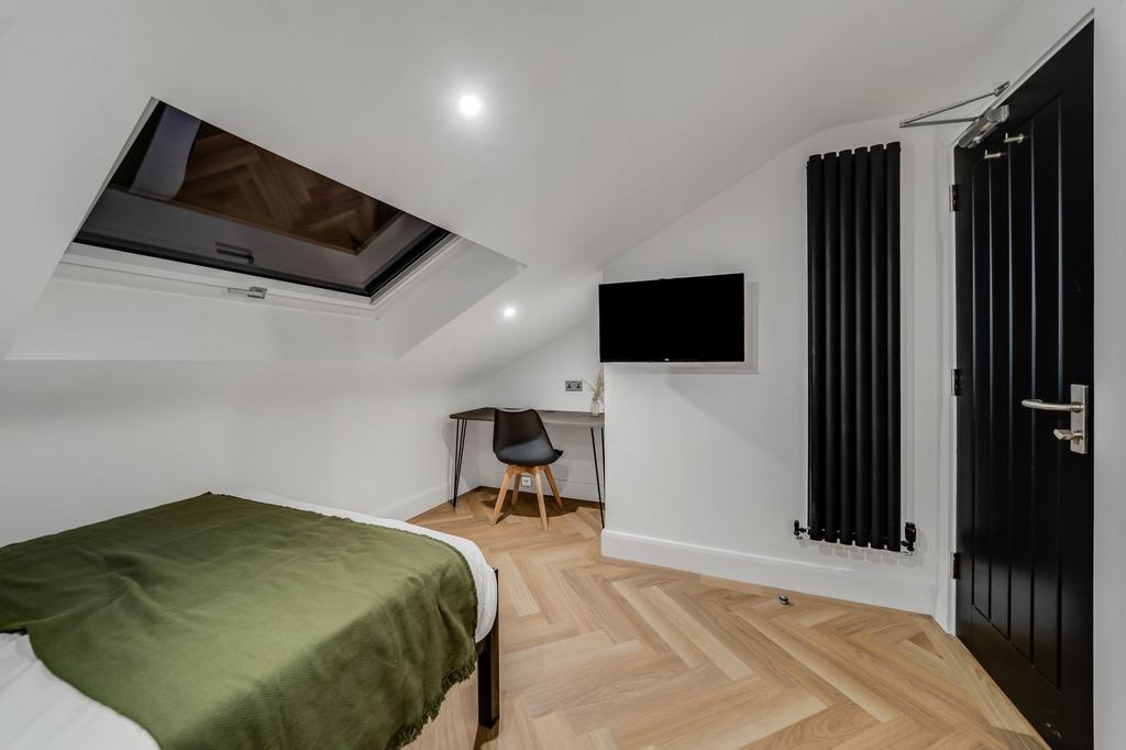 A modern bedroom with a sloped ceiling featurin...