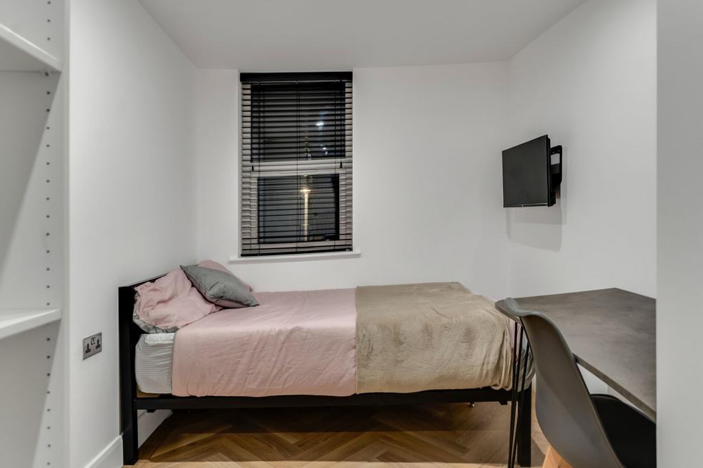 A tidy and cozy single bedroom featuring a neat...