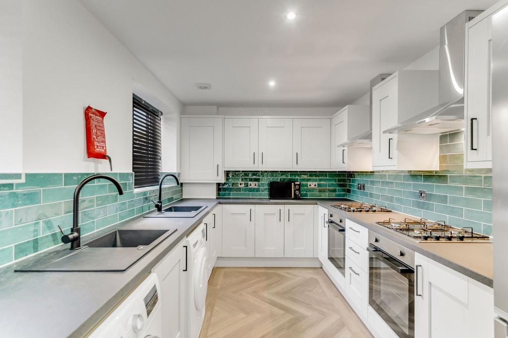 Modern kitchen featuring white cabinetry, a sle...