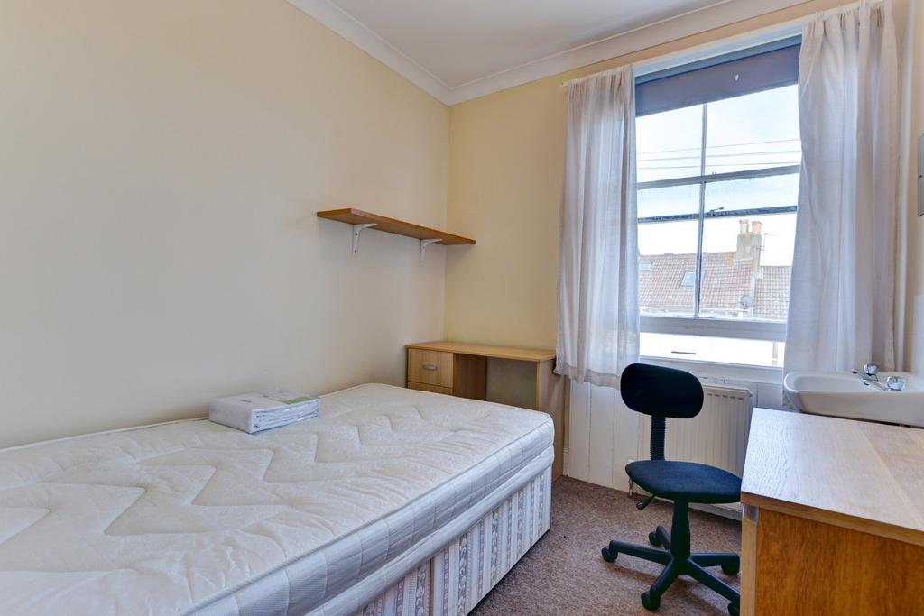 A cozy student bedroom featuring a single bed, ...