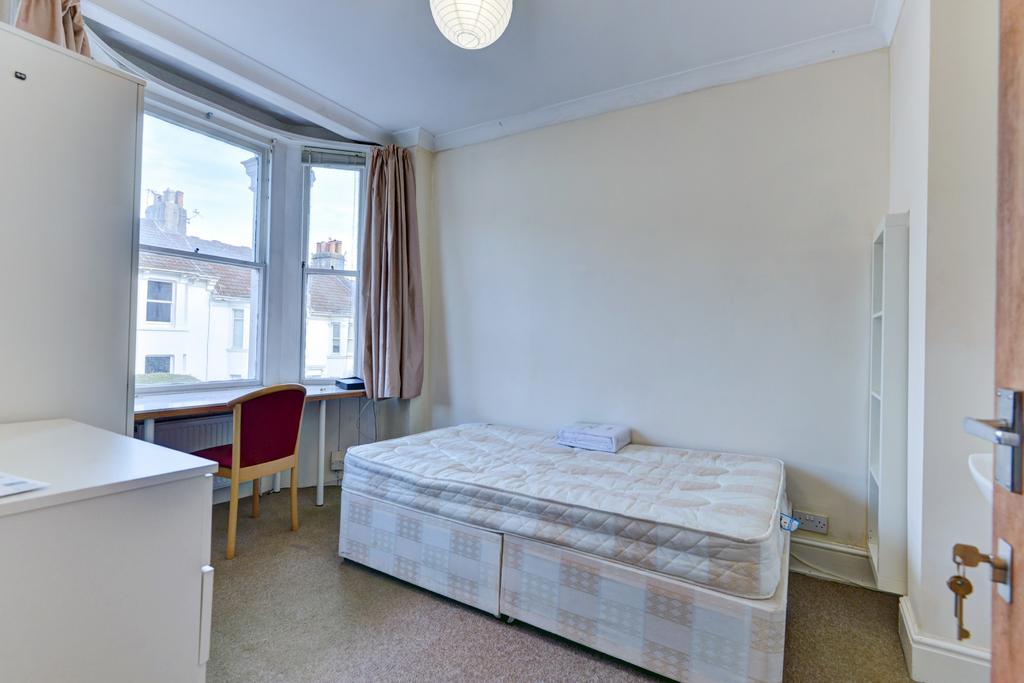 A well-lit, clean bedroom featuring a comfortab...