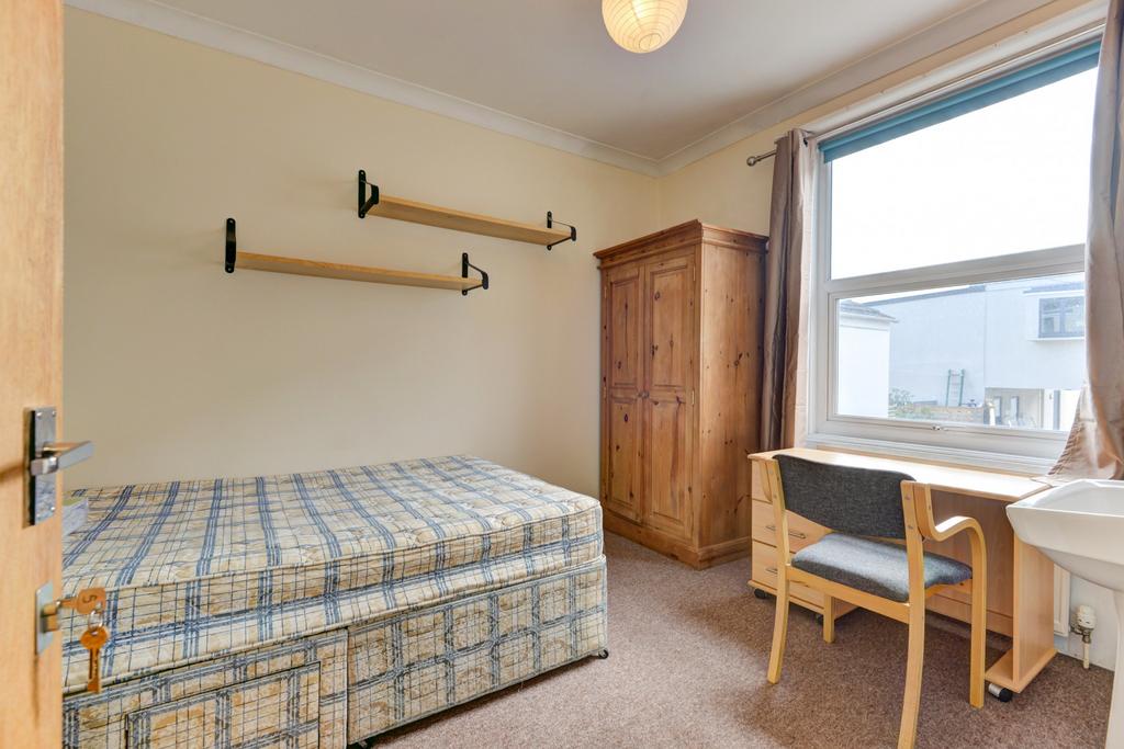 A cozy single bedroom featuring a bed with a be...