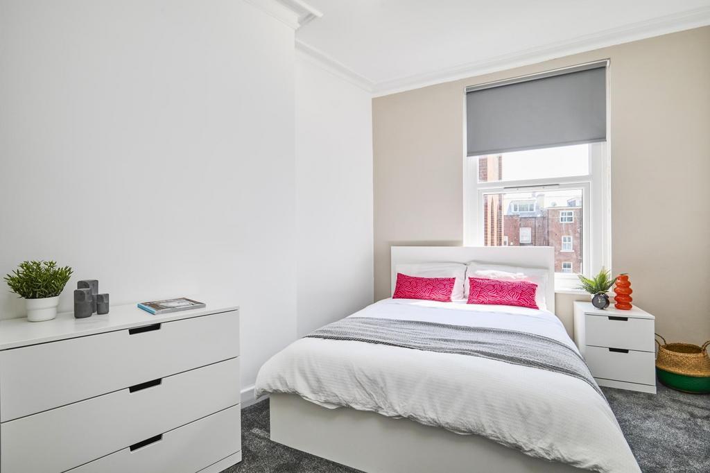 A bright and tidy bedroom featuring a comfortab...