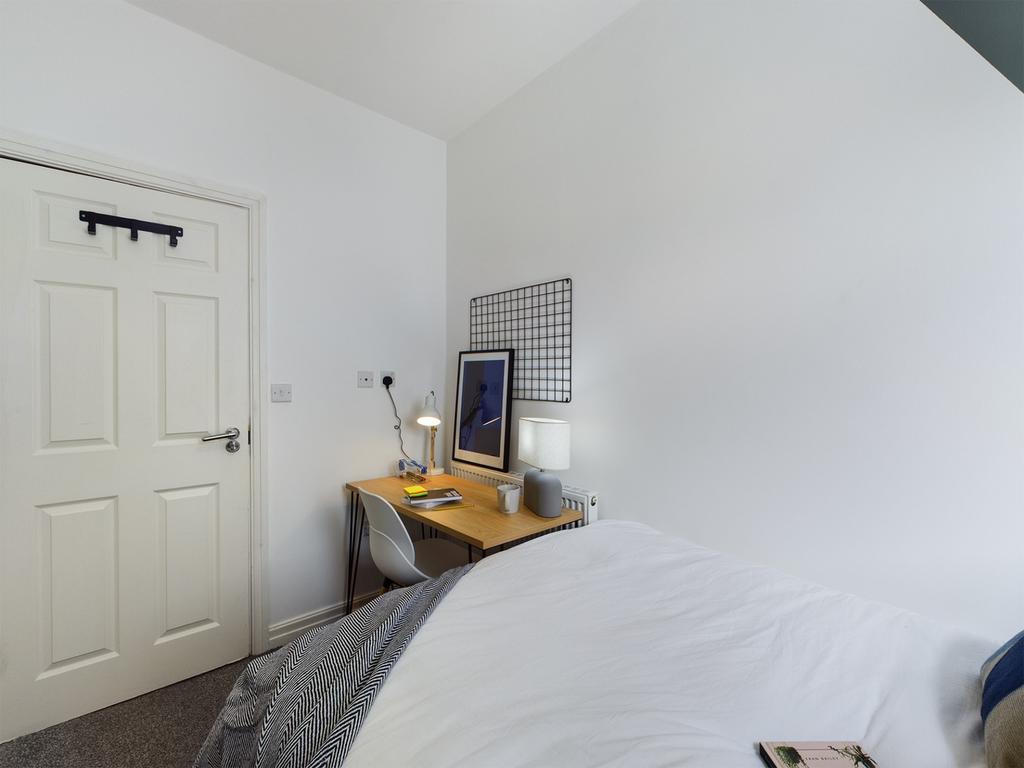 A bright and tidy double bedroom with a cozy de...