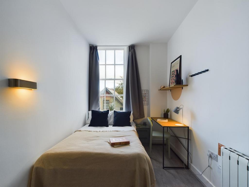 A bright and tidy single bedroom featuring a co...