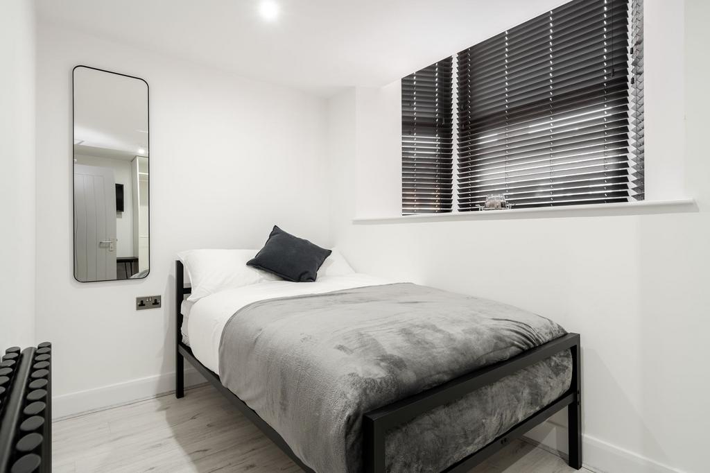 A modern, minimalist bedroom featuring a neatly...