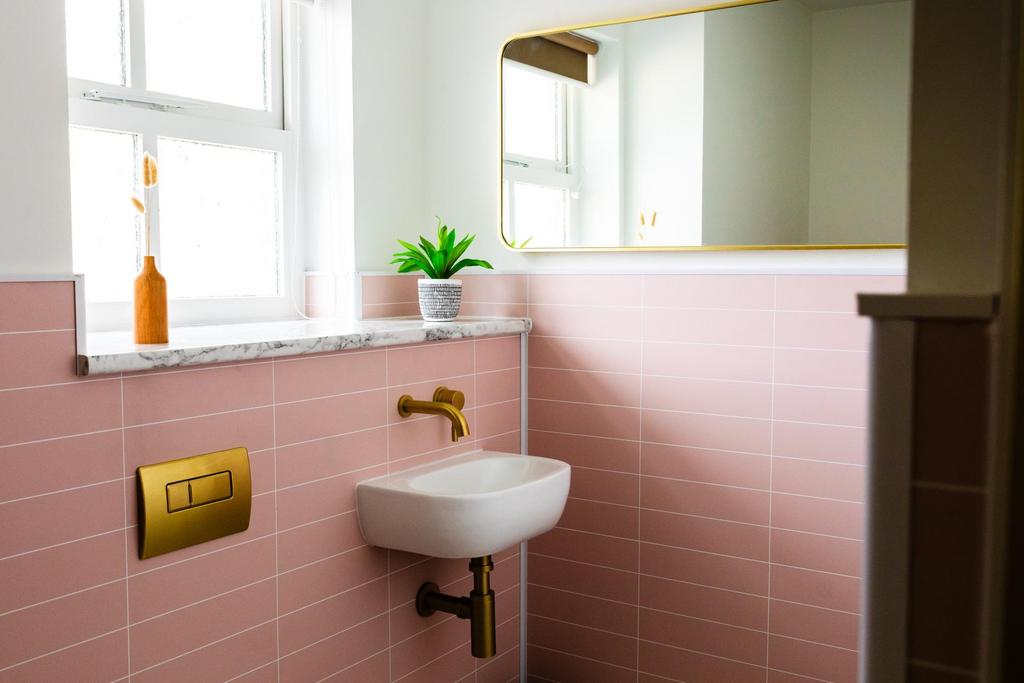 Stylish compact bathroom with pink tiled walls,...