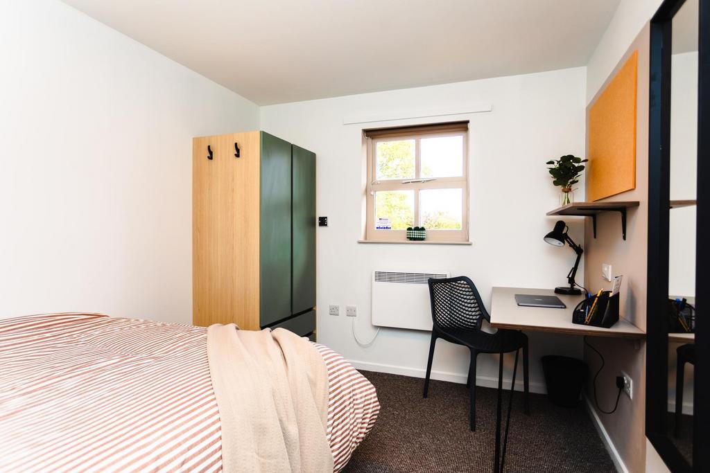 Bright, neatly furnished bedroom with a comfort...