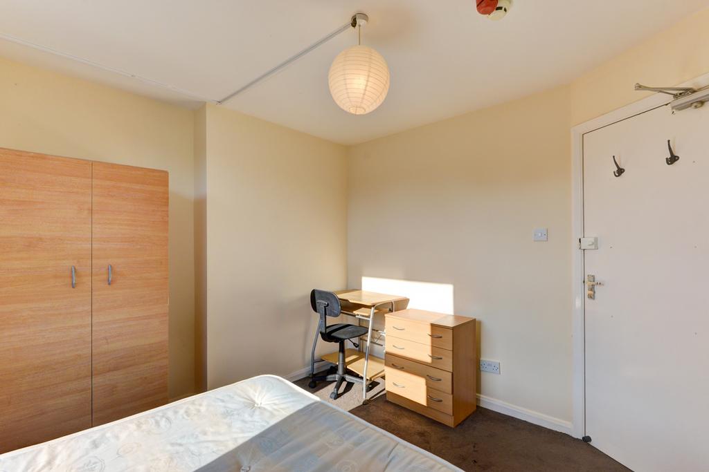 A well-lit bedroom featuring a bed, a wooden wa...