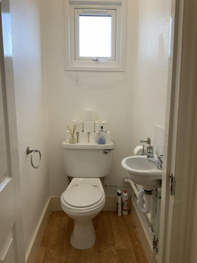 A clean and compact bathroom featuring a toilet...