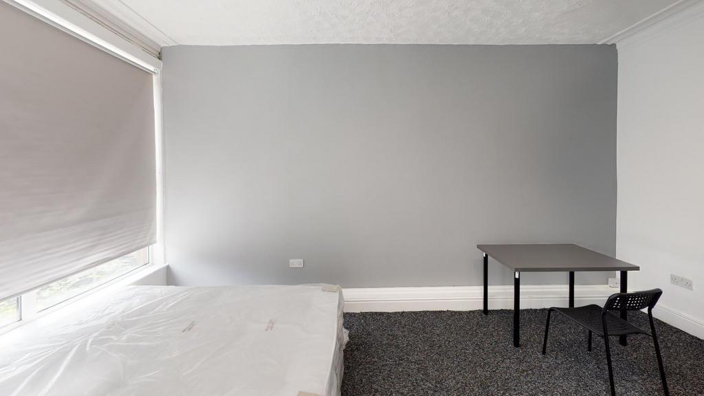 A tidy bedroom with neutral walls, featuring a ...