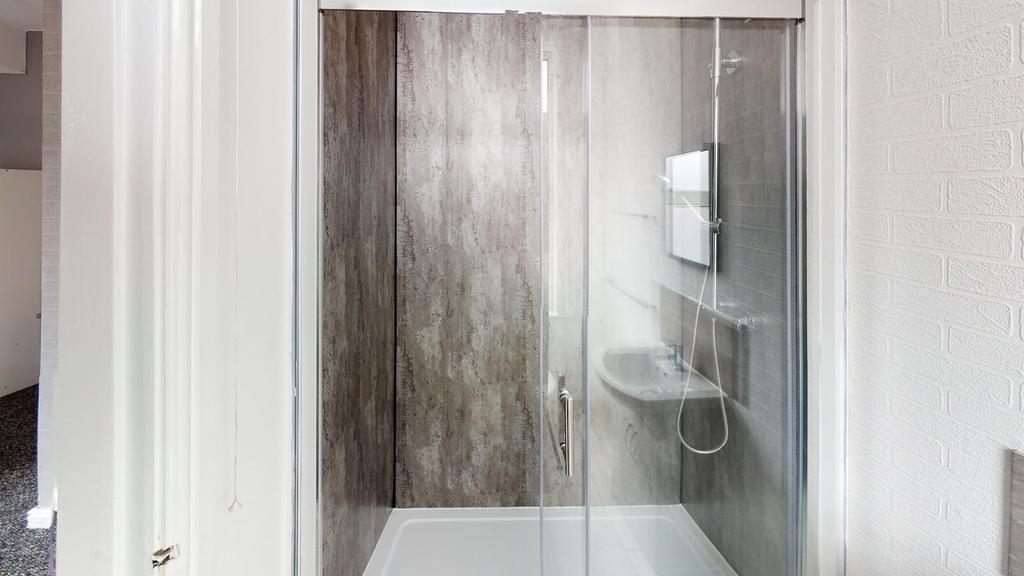 A clean and modern shower room featuring a glas...